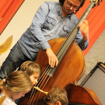 Contrabassist Ben Faes leert kinderen kennismaken met de lage bastonen van zijn historisch instrument.
